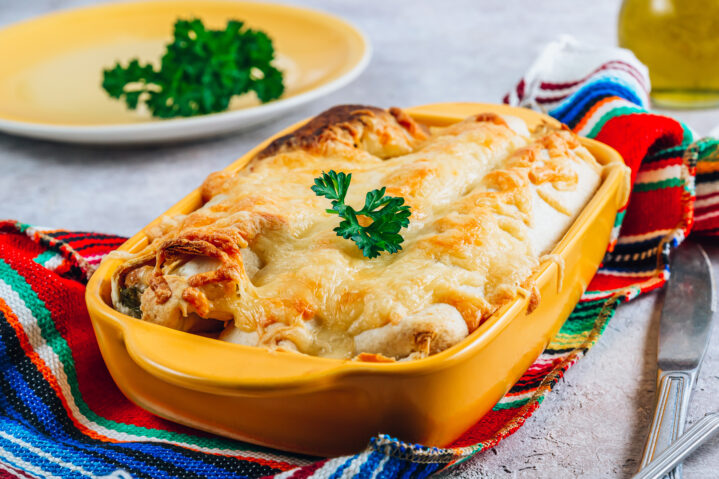 Mexican enchilada in a yellow baking dish on stone background. Selective focus