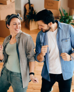 Happy couple having fun and dancing while moving into a new home.