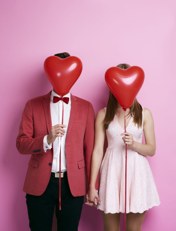Unrecognizable couple with balloon holding hands