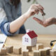 close-up-woman-s-hand-giving-house-key-man-wooden-table