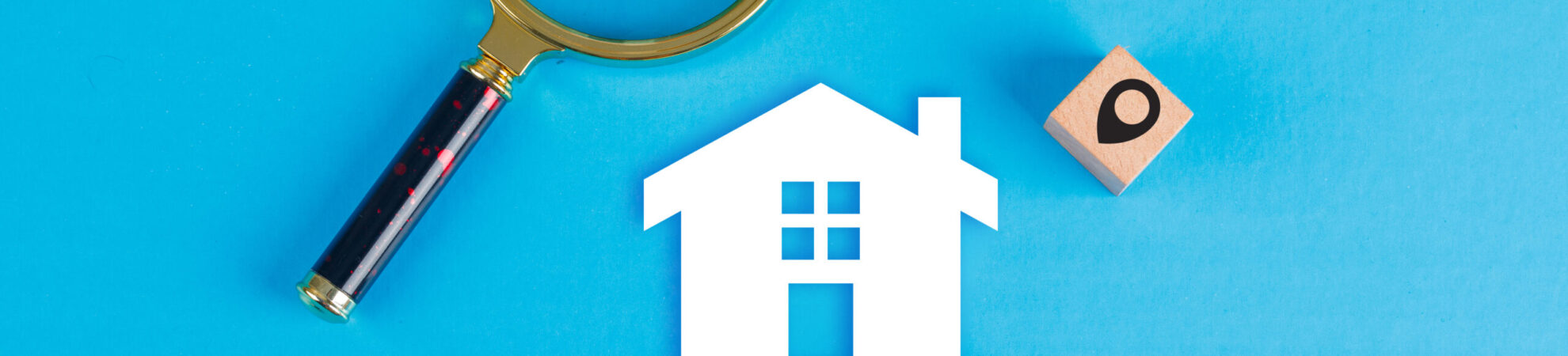 Conceptual of real estate with magnifying glass, wooden blocks, paper home icon on blue background flat lay. horizontal image