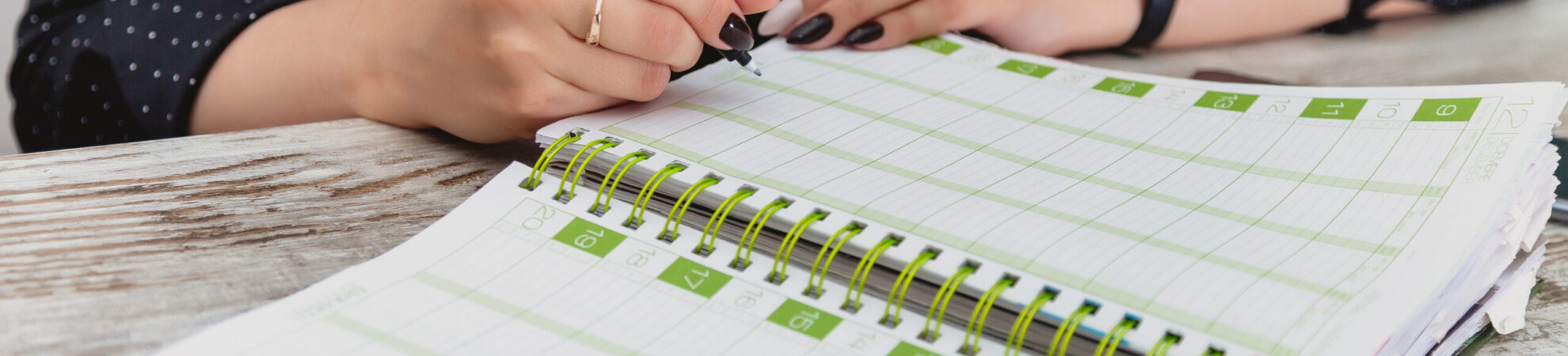 Women hands with pen write in notebook. Young girl at table in cozy office and fills out diary. Close-up of hands taking notes in magazine. Female works in an office. Planning of working time