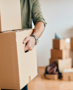 Close-up of a man with carton boxes moving into new home.
