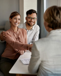 Young happy couple shaking hands with insurance agent during a meeting in the office.