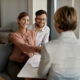 Young happy couple shaking hands with insurance agent during a meeting in the office.