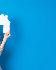 Real estate, realtors and insurance concept. Excited woman gasping and holding paper house cutout, see good deal, standing on blue background.