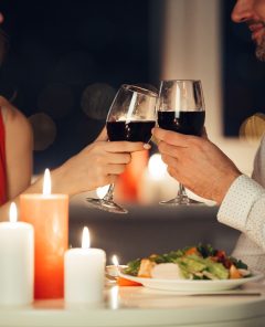 Cropped photo of young lovers having romantic dinner and drinking red wine at home